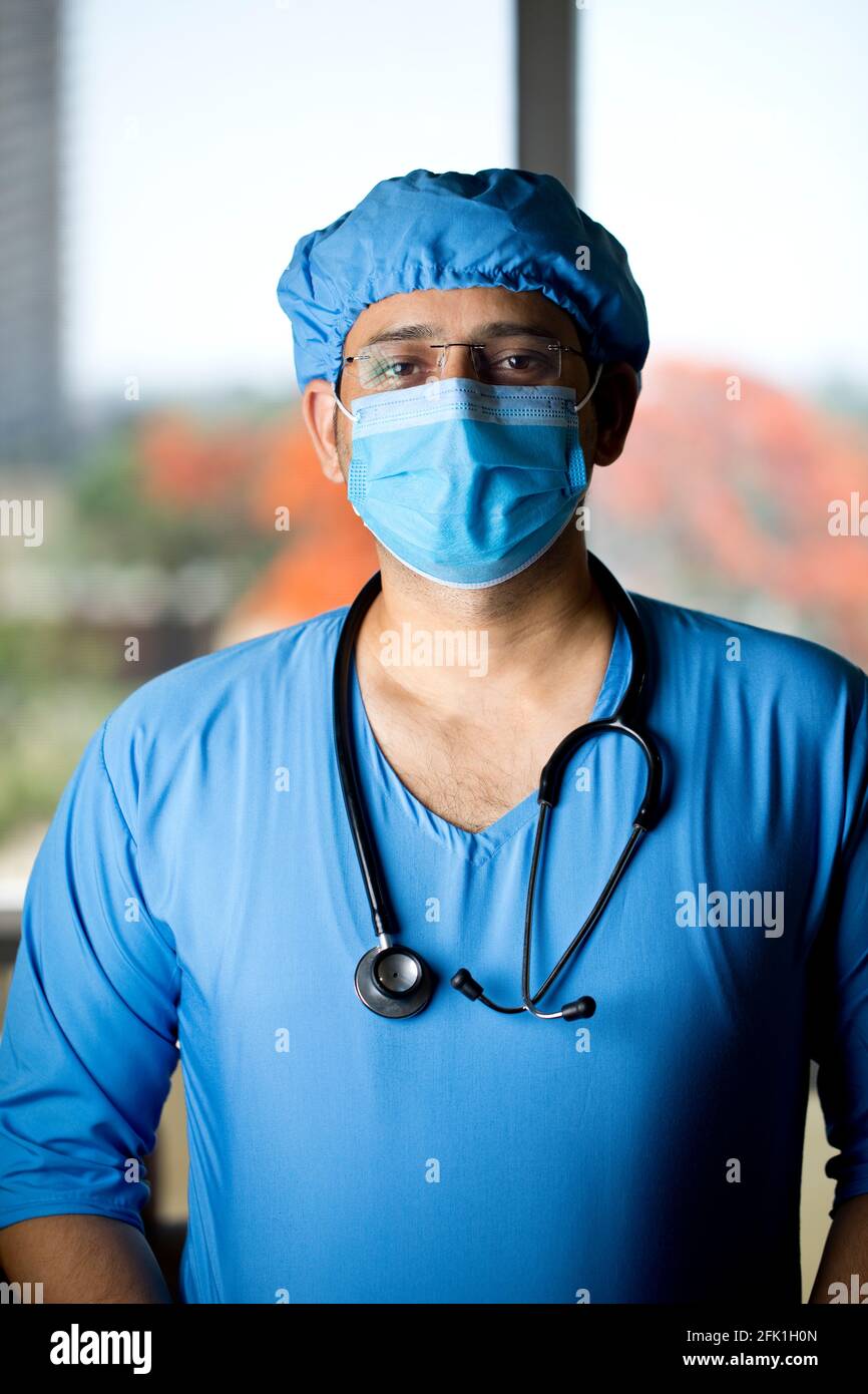 Selbstvertrauen junger männlicher Chirurg mit Gesichtsmaske, die die Kamera anschaut Stockfoto