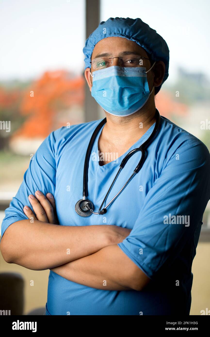 Männlicher Chirurg in Gesichtsmaske mit Armen Stockfoto