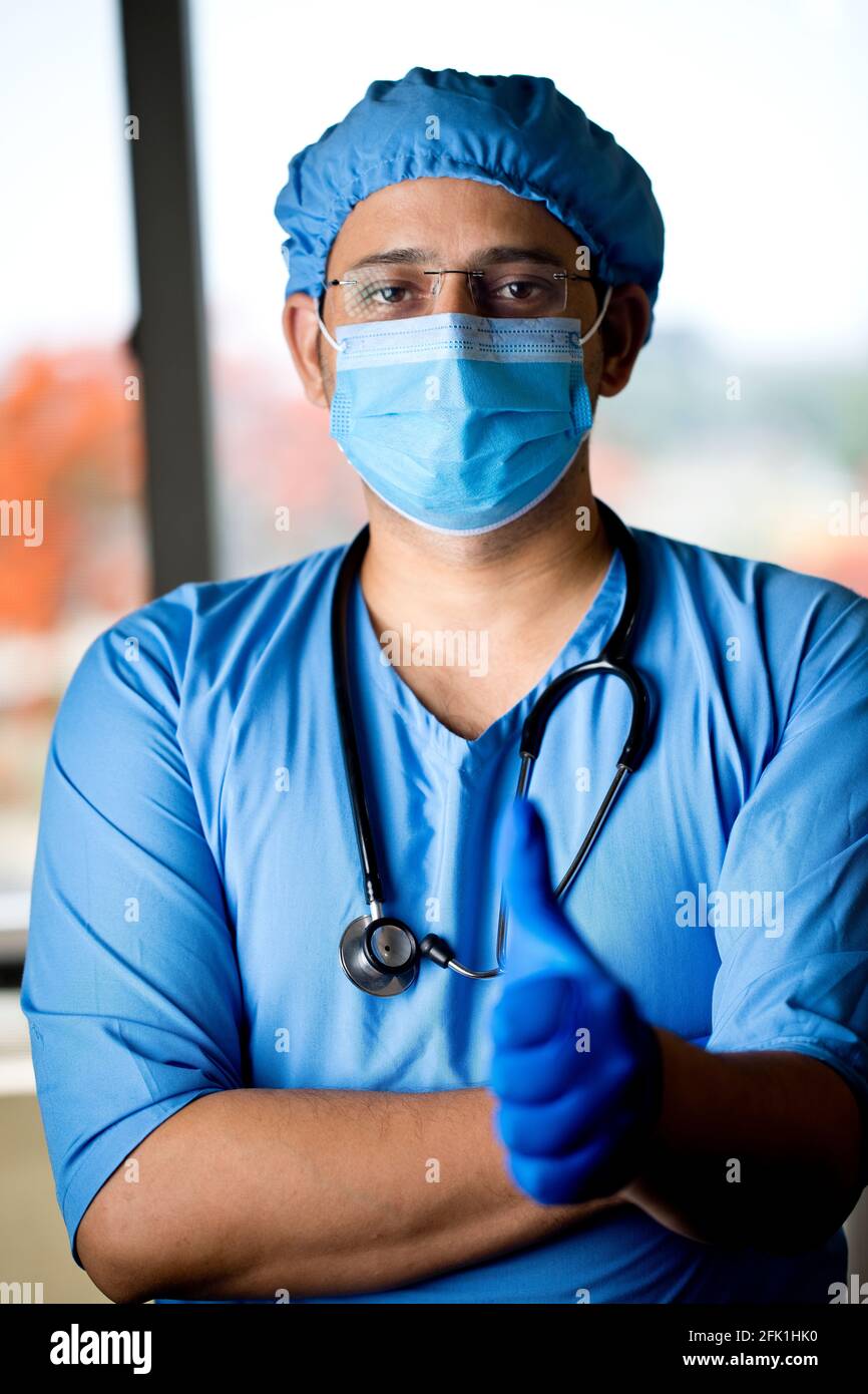 Männlicher Chirurg in Gesichtsmaske mit Armen Stockfoto