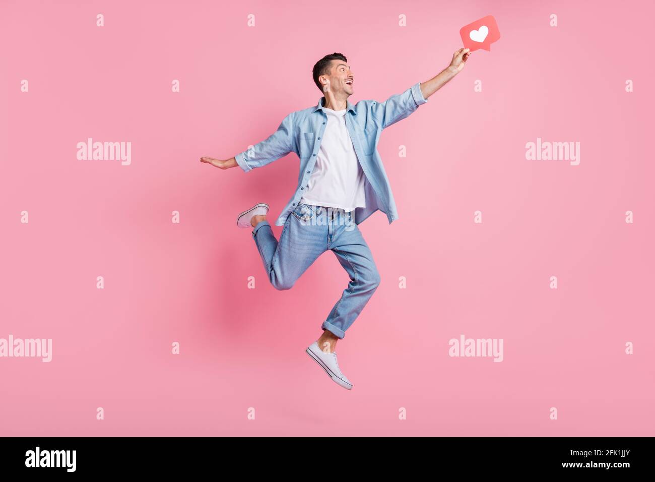 Ganzkörper-Foto von fröhlichen glücklichen Mann fangen wie Ikone Springen Sie die Luft isoliert auf pastellrosa Hintergrund Stockfoto