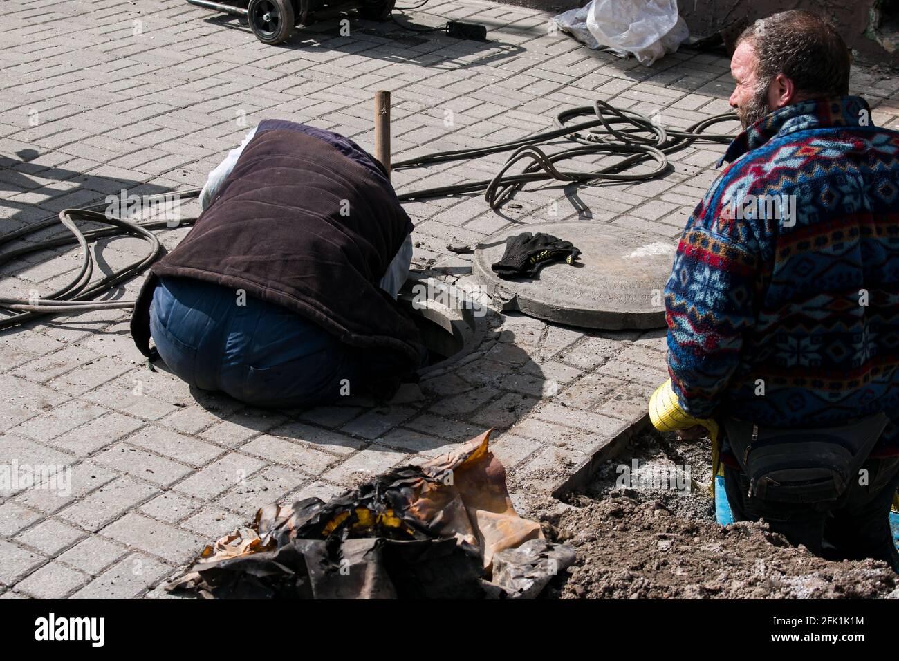 Dnepropetrovsk, Ukraine - 03.26.2021: Wasserversorger öffnen ein altes Kanalloch und ersetzen alte rostige Rohre durch neue. Stockfoto