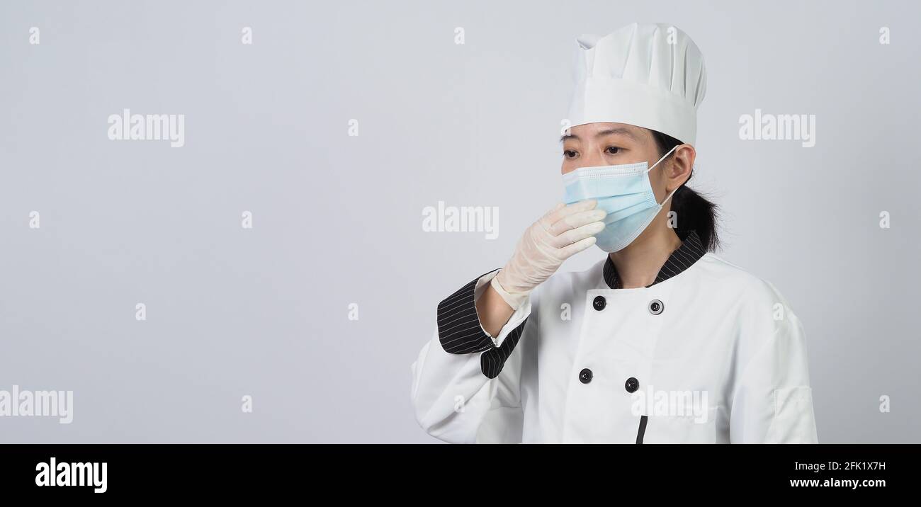 Koch trägt Gesichtsschutzmaske oder Atemschutzmaske zum Schutz vor Viruserkrankungen. Lebensmittelsicherheit und Coronavirus-Pandemie. Chef posiert Geste r Stockfoto