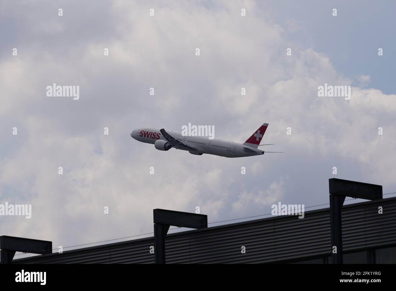 Flugzeug der Firma Swiss, die vom Flughafen Zürich abfliegt, fährt nach oben. Auf dem Hintergrund ist der Himmel bedeckt. Stockfoto