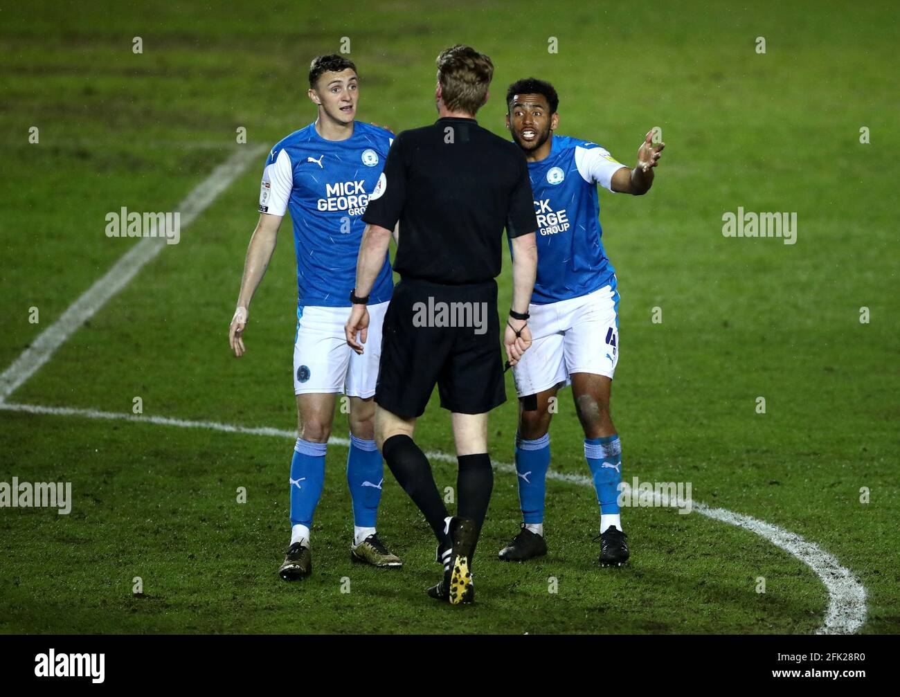 Jack Taylor (links) und Nathan Thompson von Peterborough United stehen während des Sky Bet League One-Spiels im Weston Homes Stadium, Peterborough, gegen den Schiedsrichter Scott Oldham. Bilddatum: Dienstag, 27. April 2021. Stockfoto