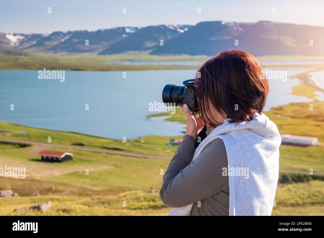 Fotografin, die mit ihrer professionellen Kamera von einem fotografiert Majestätische Küstenlandschaft bei Sonnenuntergang Stockfoto