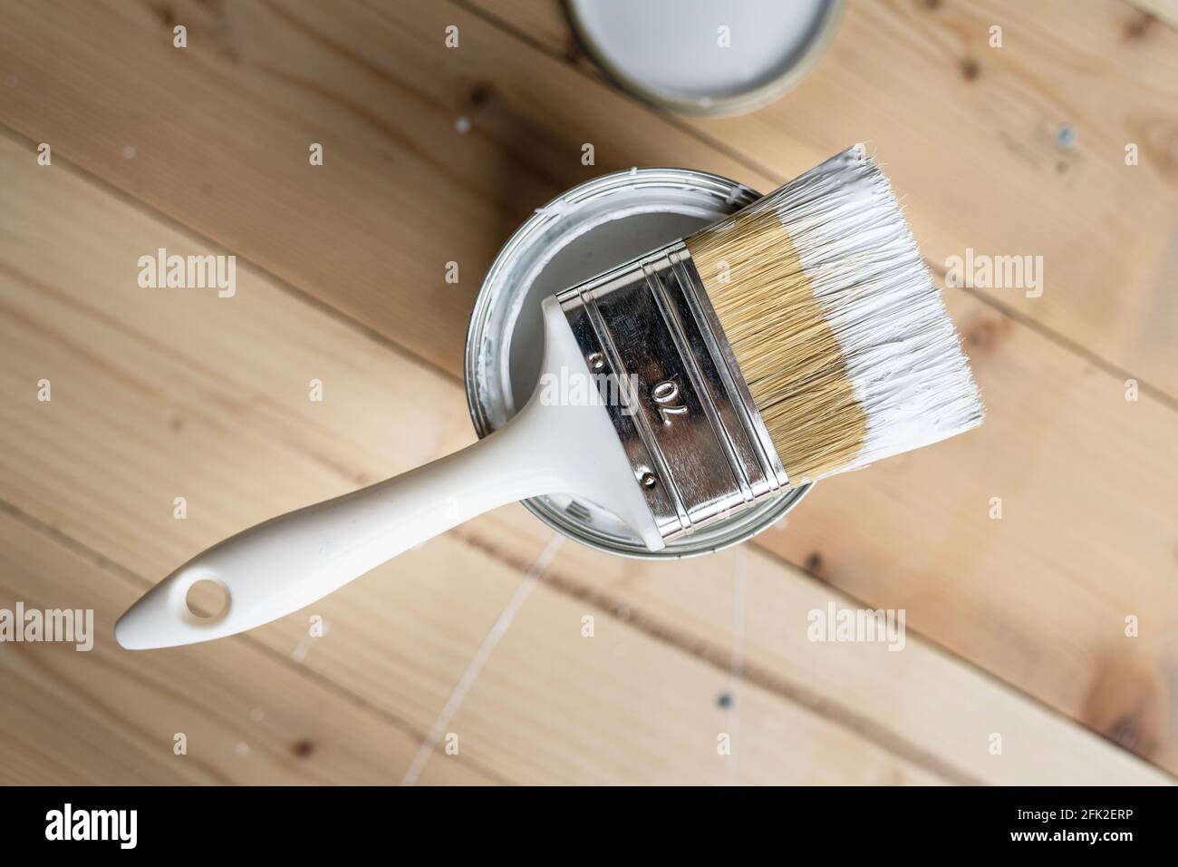 Draufsicht auf weißem Pinsel auf der geöffneten Dose Auf dem Holztisch oder Bodenbemalung und Renovierung Reparatur Konzept Stockfoto