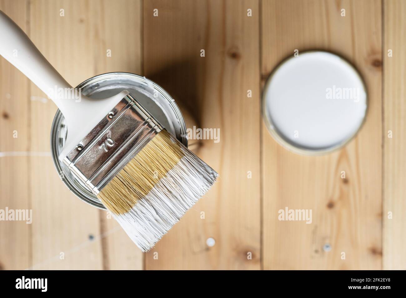 Draufsicht auf weißem Pinsel auf der geöffneten Dose Auf dem Holztisch oder Bodenbemalung und Renovierung Reparatur Konzept Stockfoto