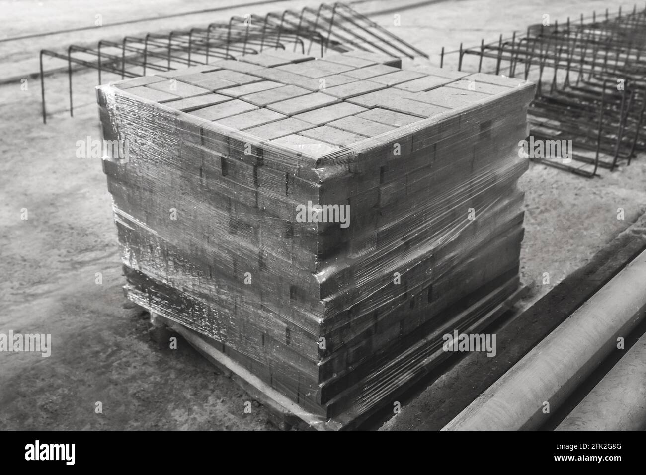 Betonblöcke in Zellophanfolie auf einer Baustelle verpackt. Betonsteine in einem Industriegebiet. Lagerung von Pflastersteinen im Lager Stockfoto