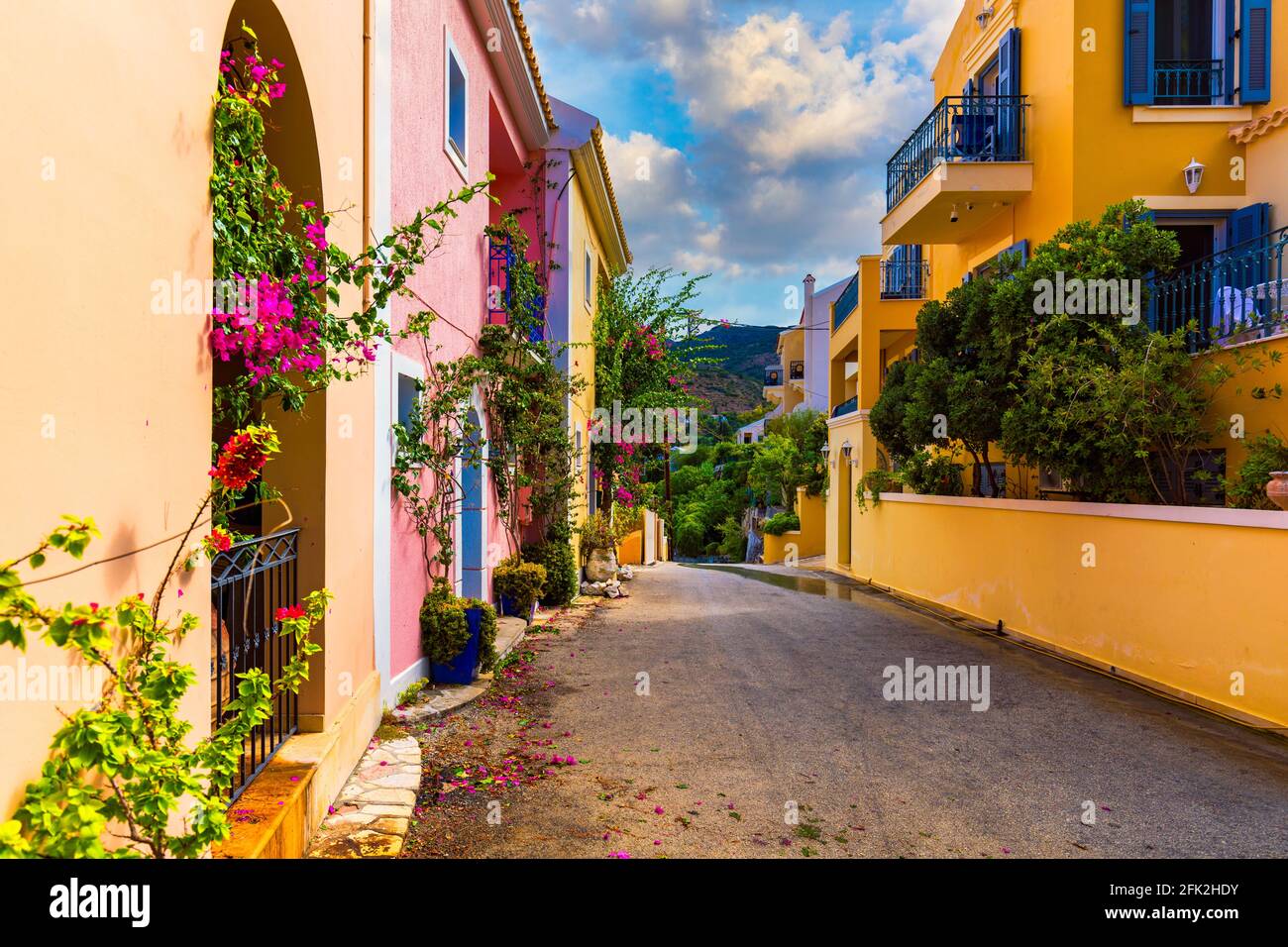 Traditionelle Straße mit griechischen Häusern mit Blumen in Assos, Insel Kefalonia. Traditionelle bunte griechische Häuser im Dorf Assos. Blühende Fuchsia pla Stockfoto