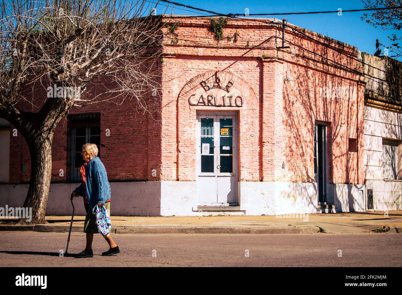 Ältere Frau, die vor der Bar Carlito läuft. Las Flores, Buenos Aires, Argentinien. Stockfoto