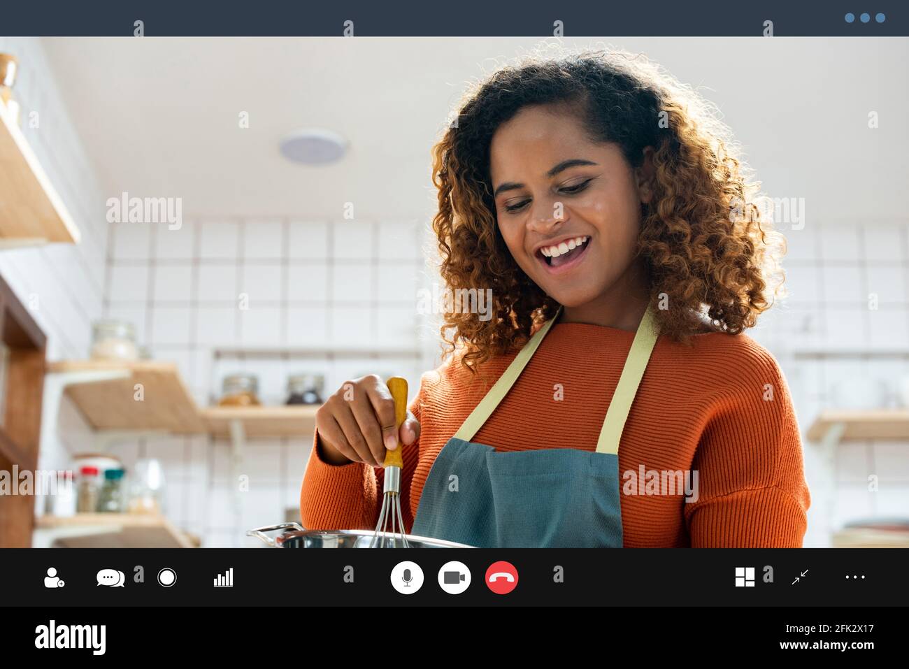 Glücklich lächelnde junge afroamerikanische Frau, die während des Telefonierens einen Videoanruf macht Kochen in der Küche zu Hause Stockfoto