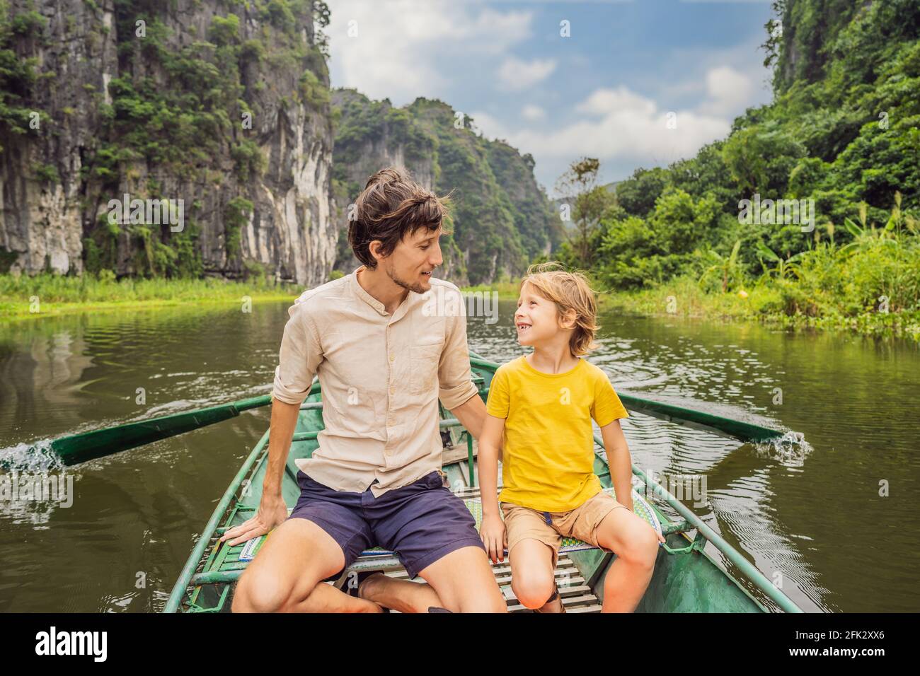 Vater und Sohn Touristen im Boot auf dem See Tam Coc, Ninh Binh, Vietnam. Es ist UNESCO-Weltkulturerbe und bekannt für seine Boothöhlenführungen. Das ist es Stockfoto