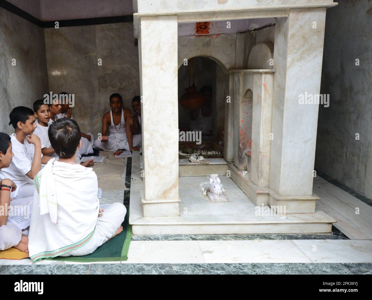 Brahmanen-Jungen studieren einen heiligen Text in einem kleinen Tempel in der Altstadt von Varanasi, Indien. Stockfoto