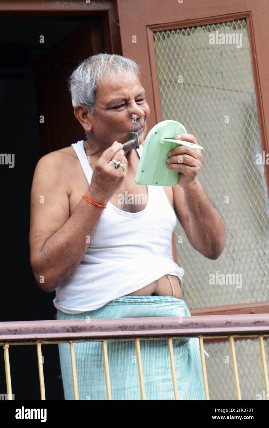 Ein Mann, der sich in der Altstadt von Varanasi, Indien, rasiert. Stockfoto