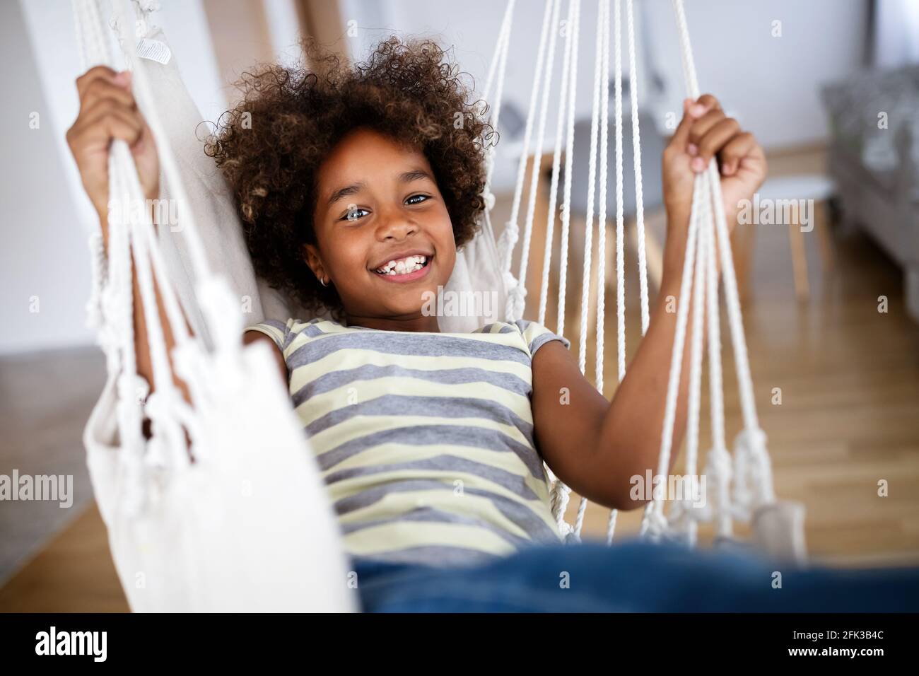 Liebenswert Mädchen genießen auf Indoor Schaukel im Wohnzimmer  Stockfotografie - Alamy