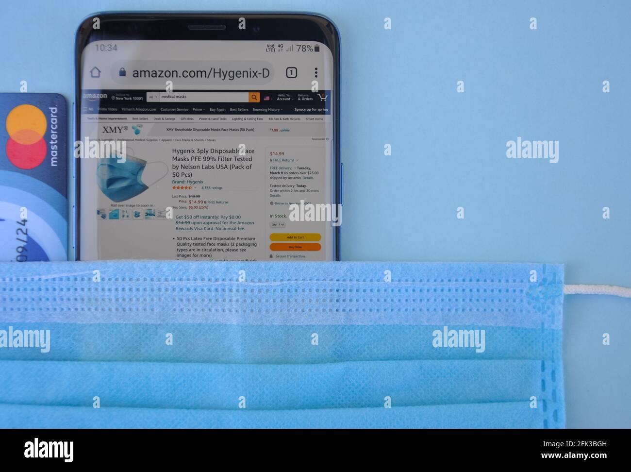 Mandi, Himachal Pradesh, Indien - 03 04 2021: Hoher Winkel des Kaufens der medizinischen Maske online mit Mastercard, Amazon-Website auf Smartphone, das ein weltweit Top-internationales elektronisches Handelsunternehmen ist Stockfoto