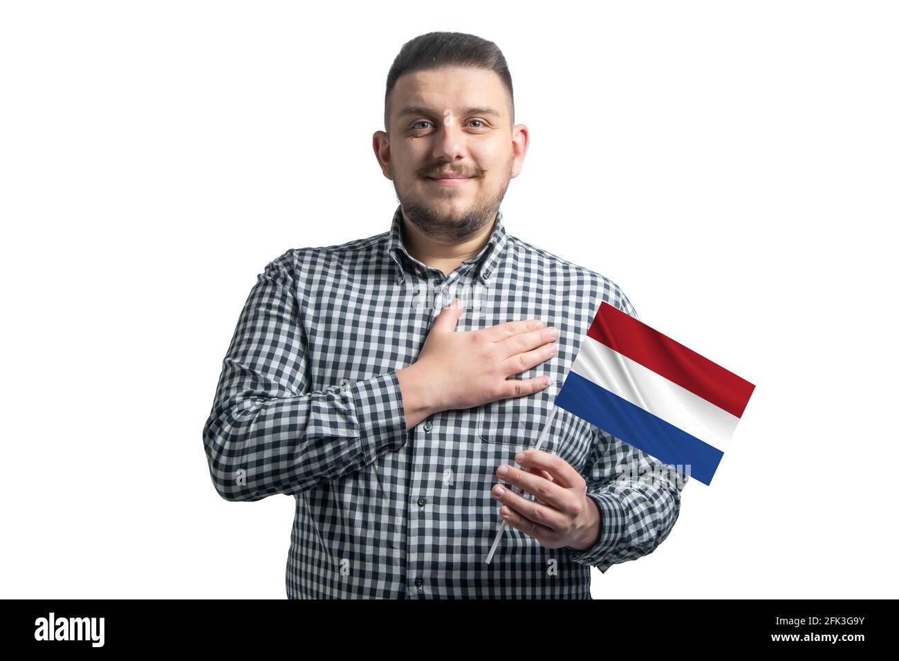 Weißer Kerl mit einer Flagge der Niederlande und hält seine Hand auf seinem Herzen isoliert auf einem weißen Hintergrund mit Liebe zu den Niederlanden. Stockfoto