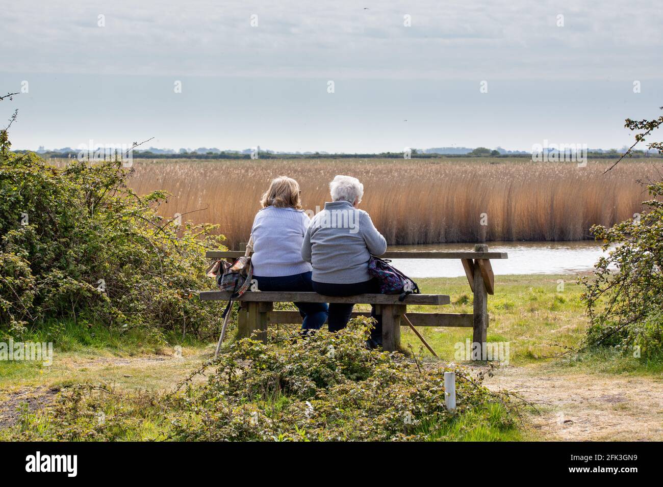 Eine Erwachsene Mutter und Tochter, die sich auf einer Bank in einem Naturschutzgebiet auf dem Land ausruhen, Farlington Marshes Stockfoto