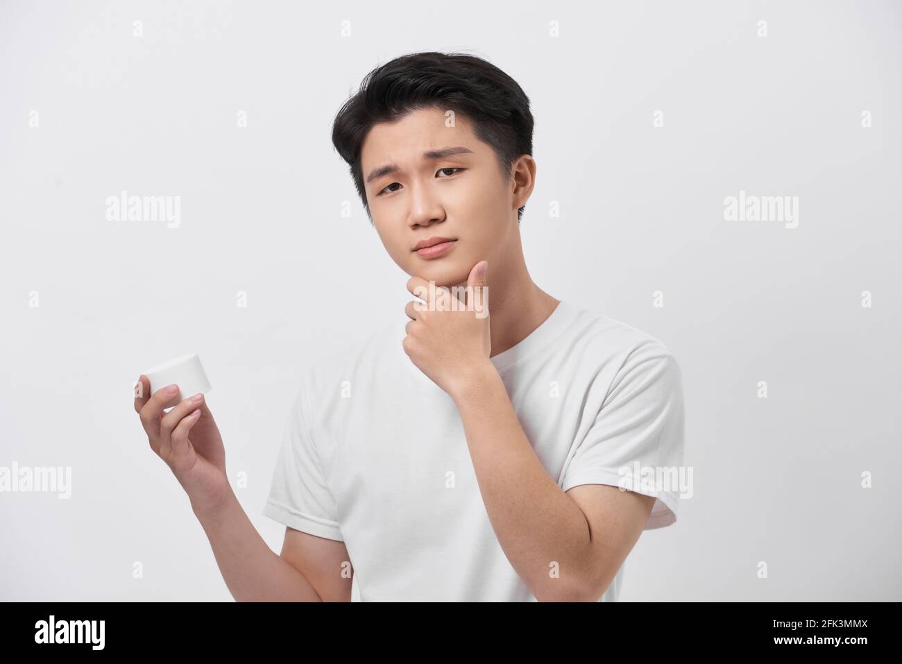 Schönheit, Hautpflege und Menschen Konzept - lächelnder junger Mann mit Creme-Glas auf grauem Hintergrund Stockfoto