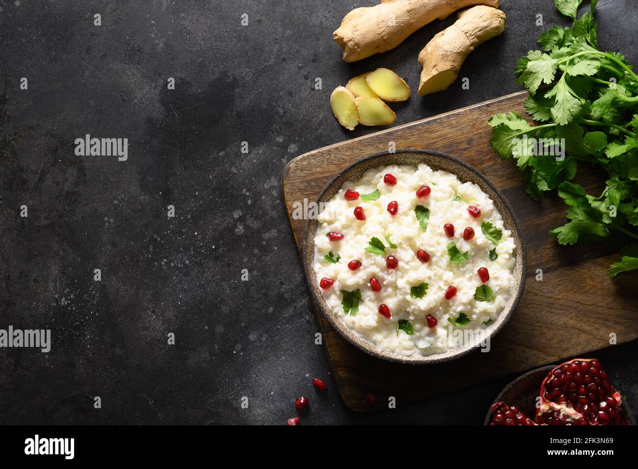 Quark mit Granatapfel, Koriander, Senfkörnern, Ingwer auf schwarzem Hintergrund. Indische Südküche Stockfoto