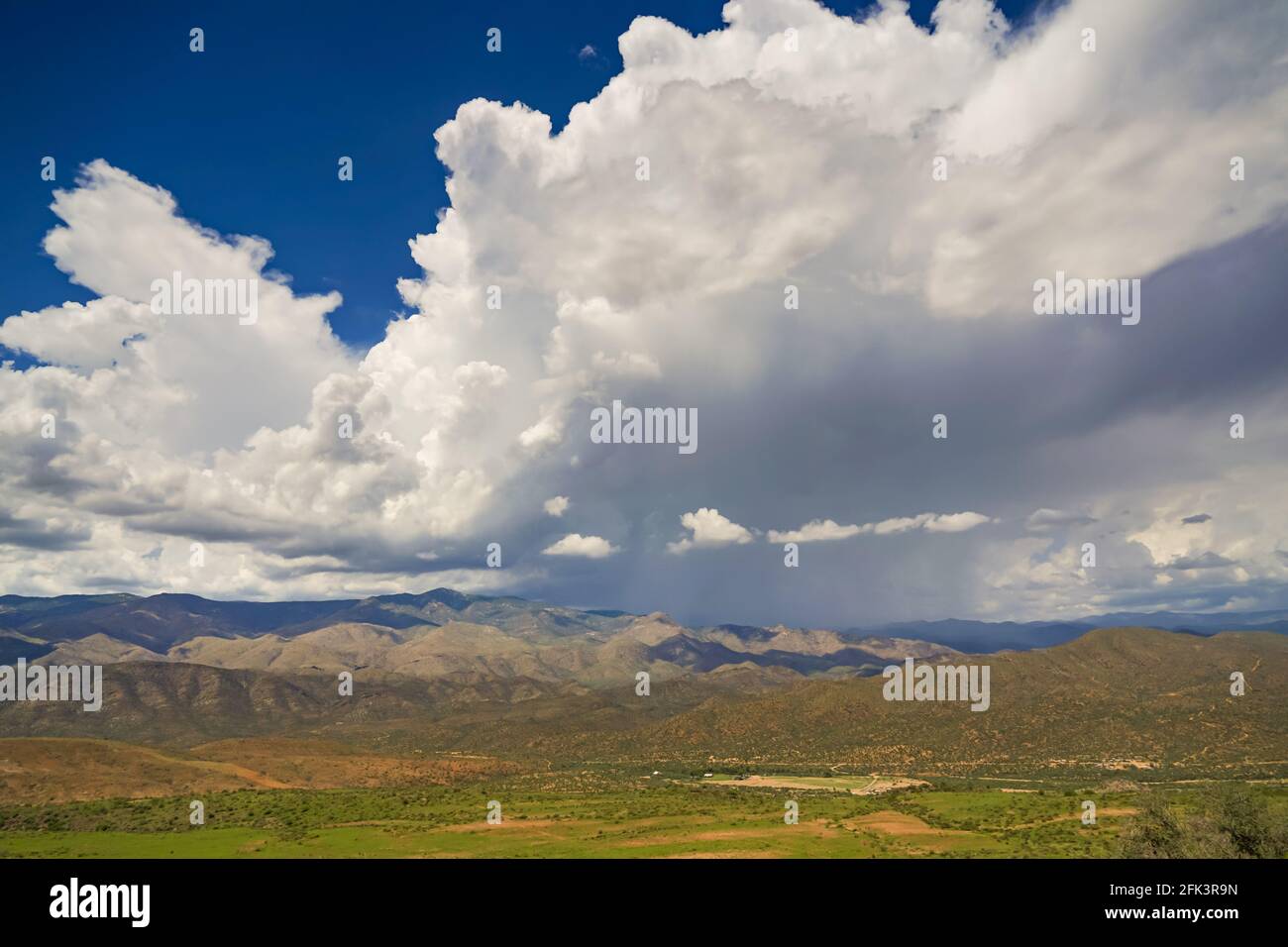 Riesige Gewitterwolken schwimmen über einem Hügel in der Wüstenlandschaft Stockfoto