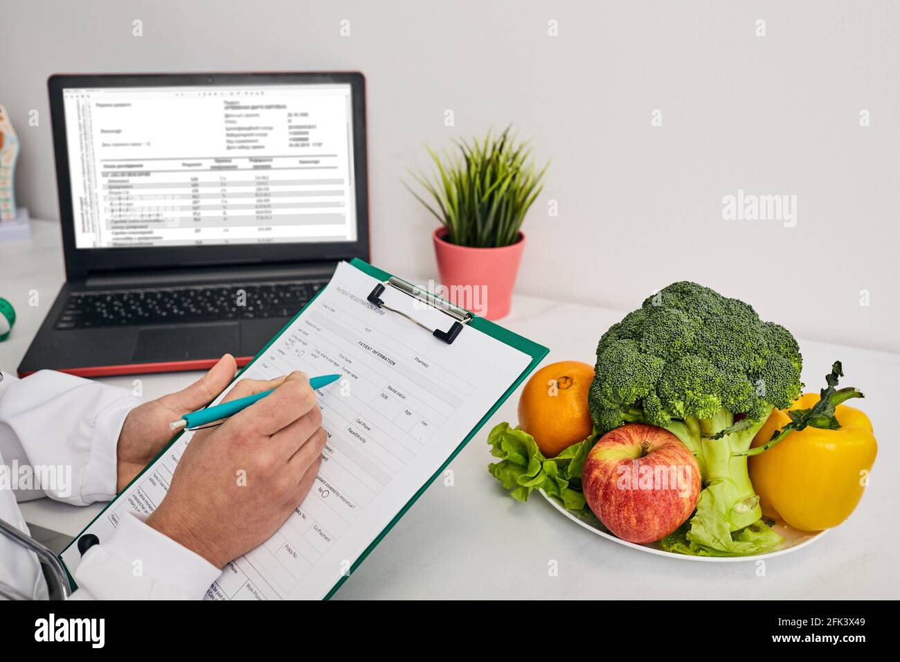 Der klinische Ernährungsberater oder Ernährungsberater erstellt einen personalisierten Ernährungsplan für einen Patienten, der Gemüse und Obst umfasst. Gesunde Ernährung Stockfoto