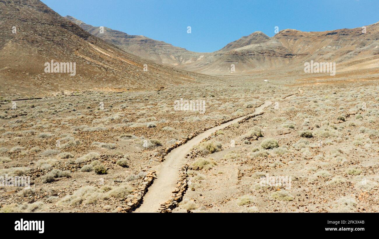 Luftaufnahmen: Drohnenansicht einer Wüstenlandschaft mit einer Straße, die in ein Tal führt Stockfoto