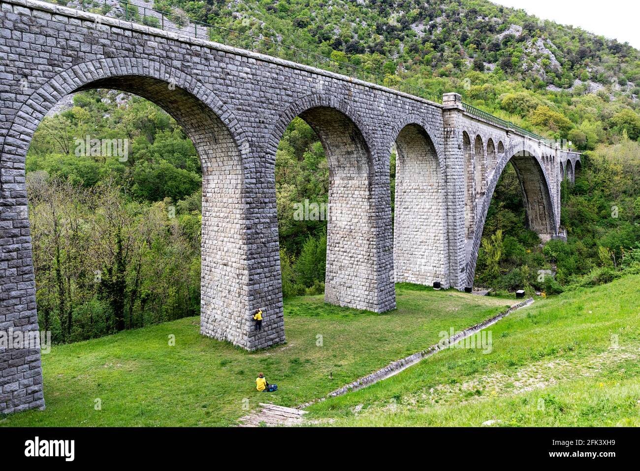 Junge klettert auf der Solkan-Brücke auf dem Fluss Soca (Isonzo), Mutter beobachtet ihn, Slowenien Stockfoto