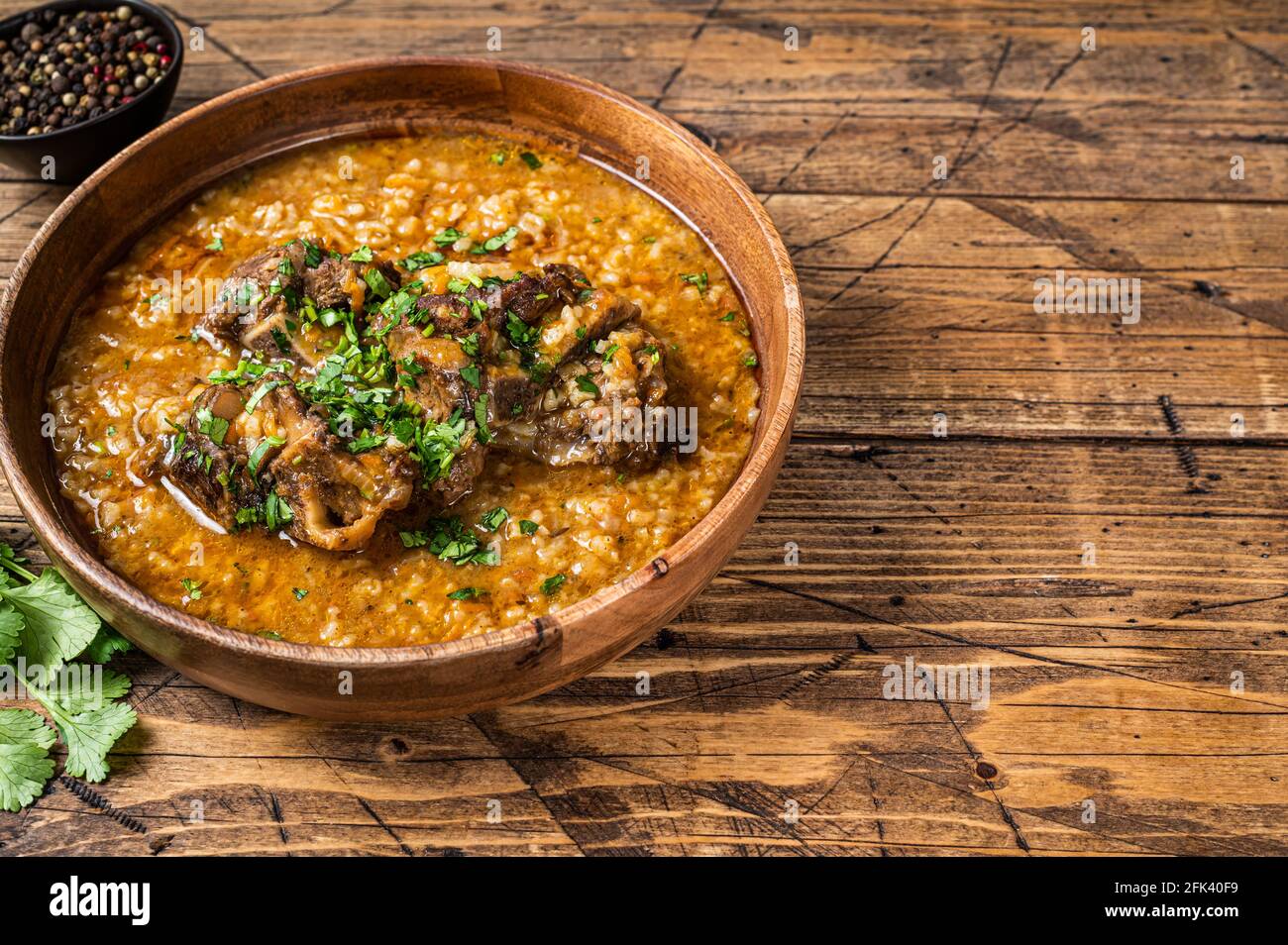 Georgische Kharcho Lammfleischsuppe mit Reis, Tomaten und Gewürzen in einer Holzschüssel. Holzhintergrund. Draufsicht. Speicherplatz kopieren Stockfoto