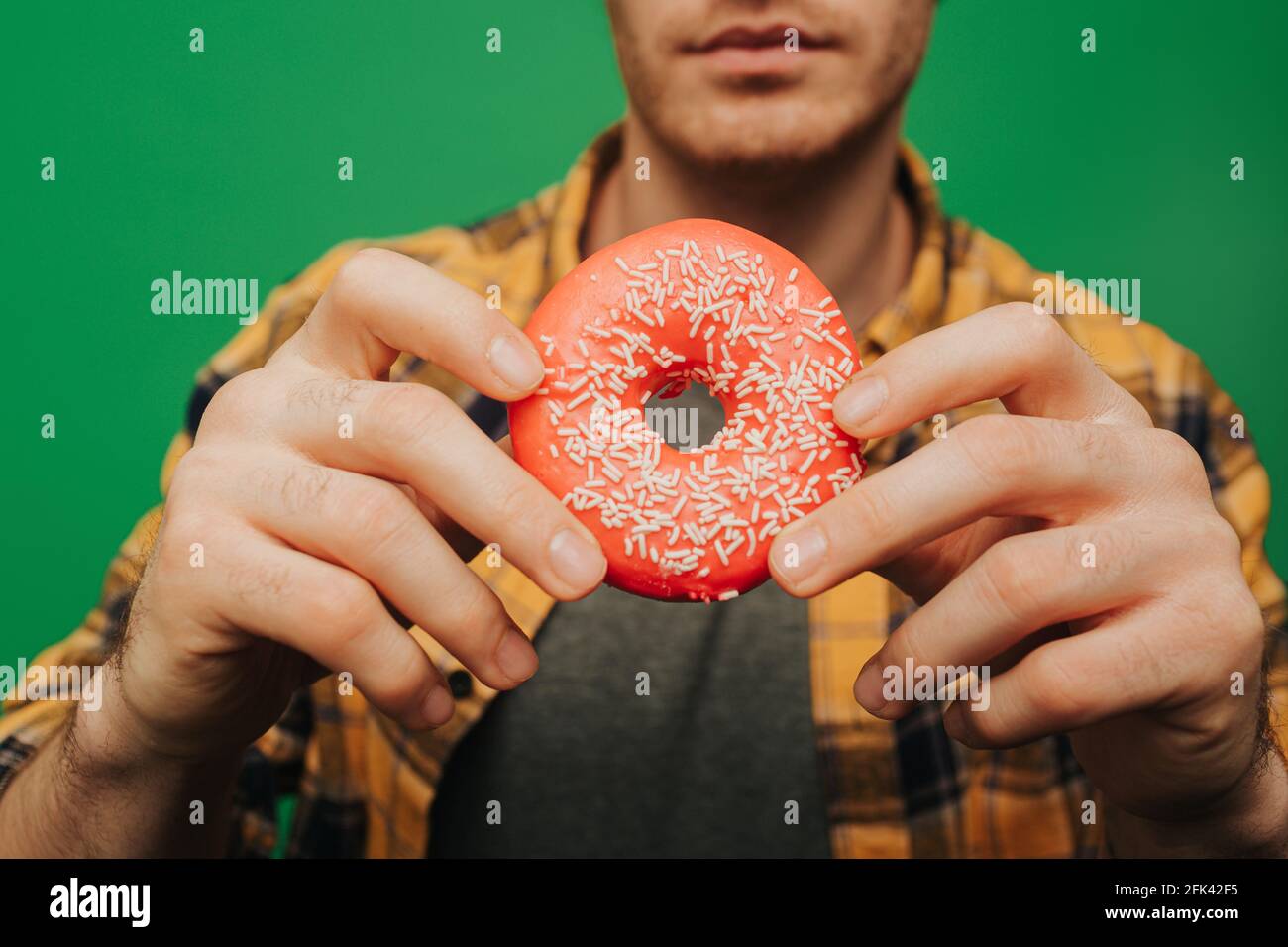 Der Mensch hält Donut, isoliert auf grünem Hintergrund Stockfoto