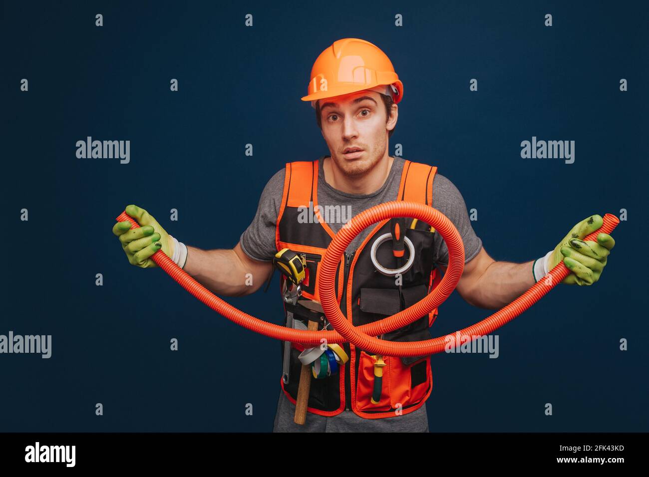 Neugieriger Baumeister hält die Trompete, isoliert auf blauem Hintergrund Stockfoto