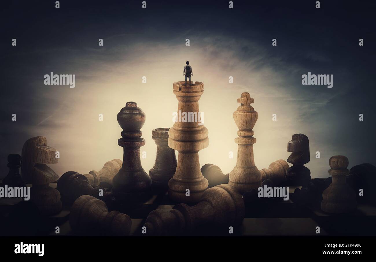 Schachspieler, der Erfolg erzielt. Surreale und konzeptuelle Szene einer winzigen Person, die auf dem Schachbrett zwischen riesigen Schachfiguren steht. Überwinden von Stockfoto