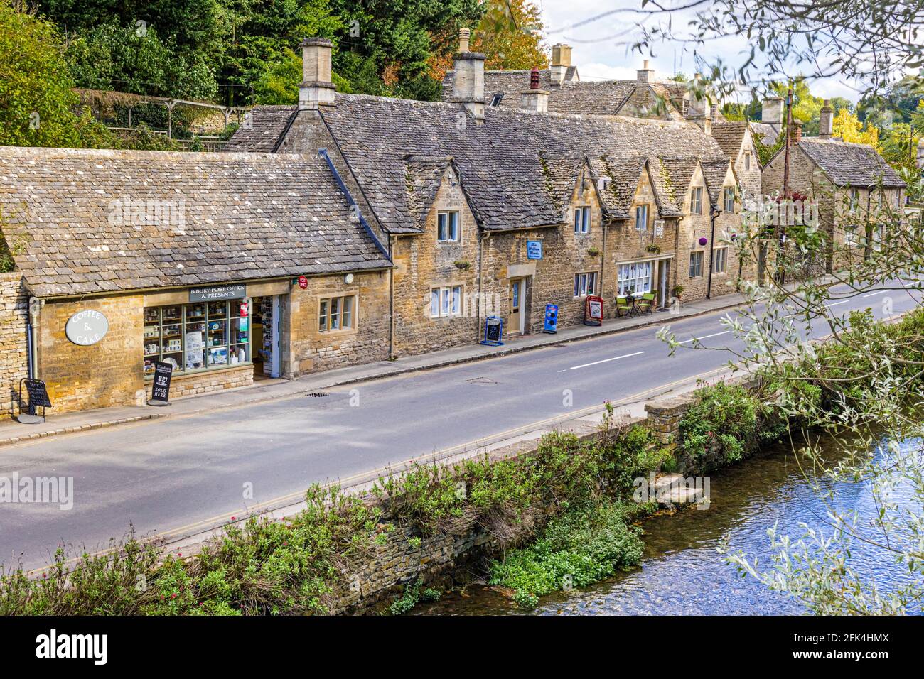 Ferienhäuser und Geschäfte am Fluss Coln im Cotswold-Dorf Bibury, Gloucestershire, Großbritannien Stockfoto