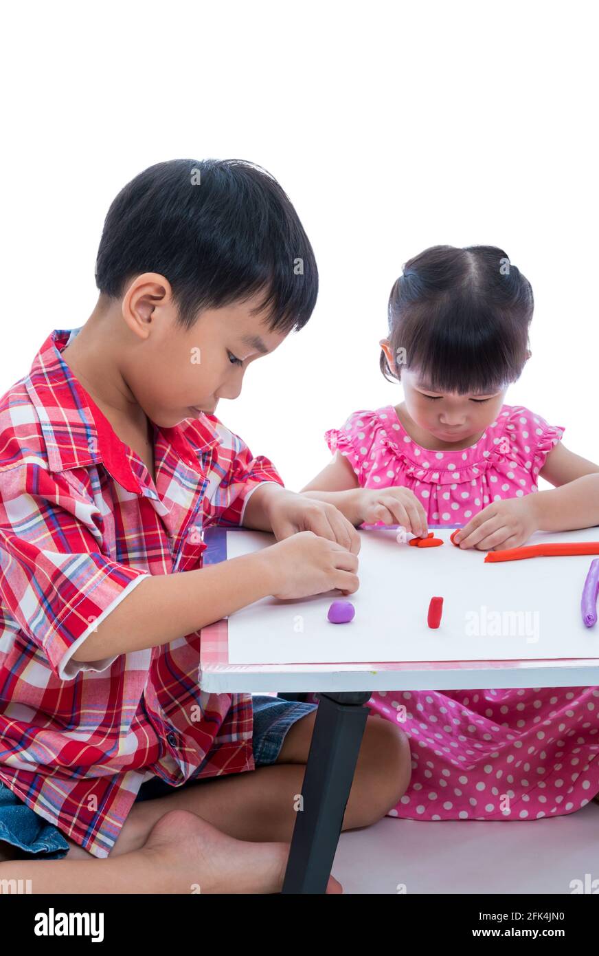 Kleine asiatische Kinder spielen und erstellen Spielzeug aus Spielteig auf dem Tisch, auf weißem Hintergrund. Stärken Sie die Phantasie des Kindes Stockfoto
