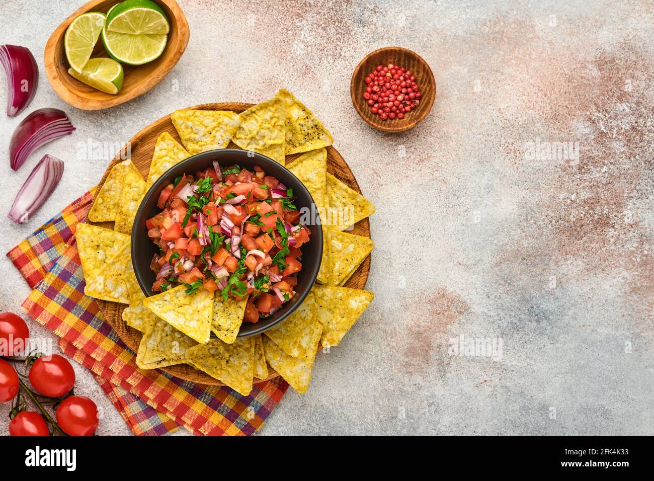 Traditionelle mexikanische Tomatensauce Salsa mit Nachos und Zutaten Tomaten, chile, Knoblauch, Zwiebel auf hellem Schieferstein Hintergrund. Konzept des lateinischen am Stockfoto