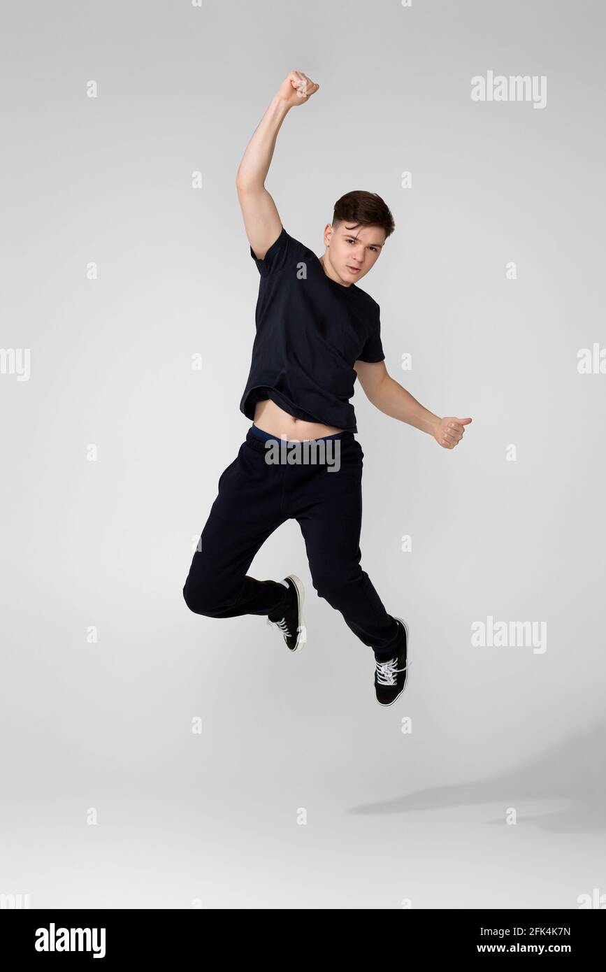Hübscher junger Mann in schwarzem T-Shirt, der springt. Stockfoto