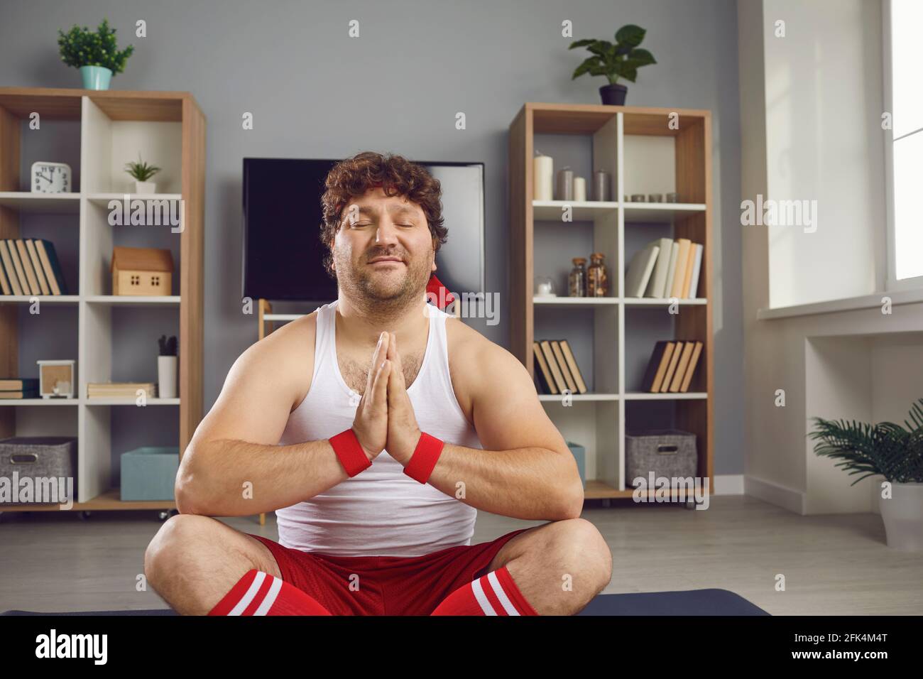 Friedliche dicke lustige Kerl in Sportkleidung meditieren beten entspannende Lotus Pose Stockfoto