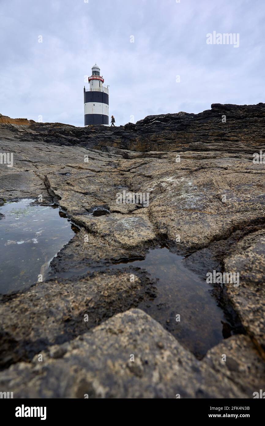 Große Risse in Felsen mit Hook Leuchtturm am Boden. In Wexford, Irland. Stockfoto