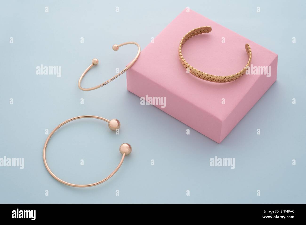 Set von modernen goldenen Armbändern auf Pastellfarben Hintergrund Stockfoto