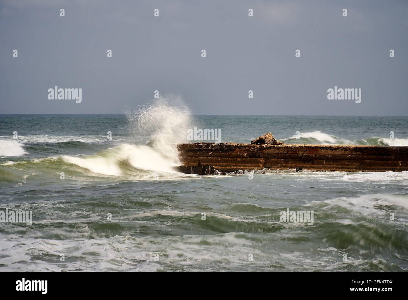 Ein Stück alte verlassene Pier während des Seesturms. Wellen an einem trüben, bösen Tag. Stockfoto
