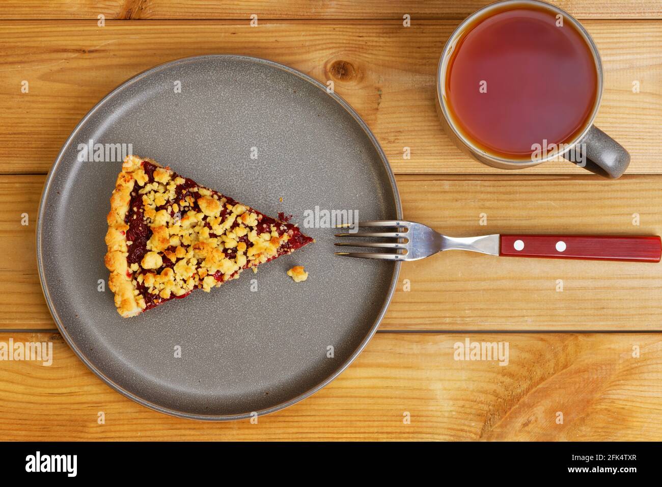 Nahaufnahme Stück hausgemachter Kirschkuchen und Tasse Tee auf Holztisch. Draufsicht. Stockfoto