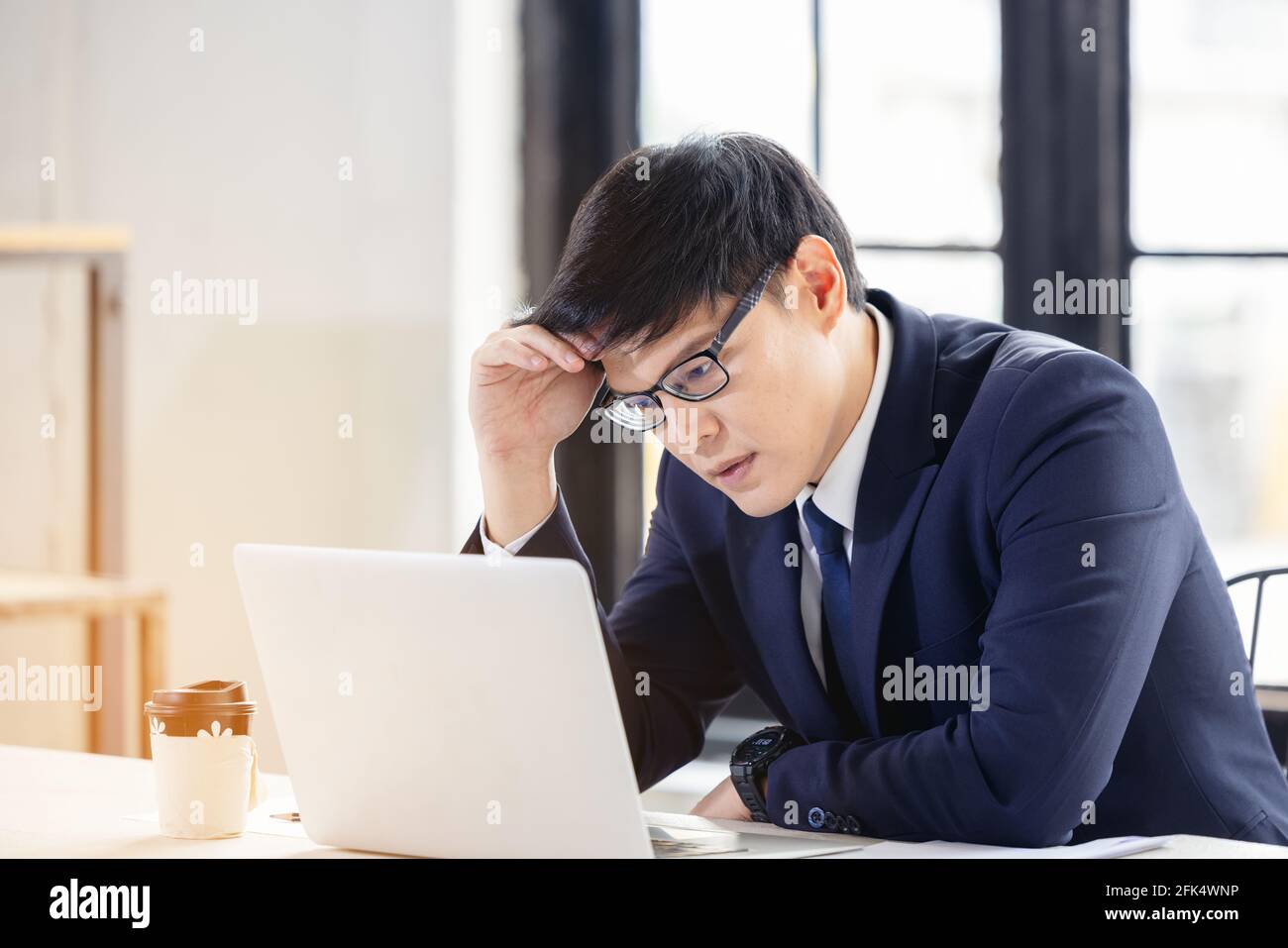 Besorgt und enttäuscht Remote online arbeitenden Mann in lässigem Outfit Mit Laptop sitzt in einem Coworking / Home Office bei Ein Schreibtisch Stockfoto