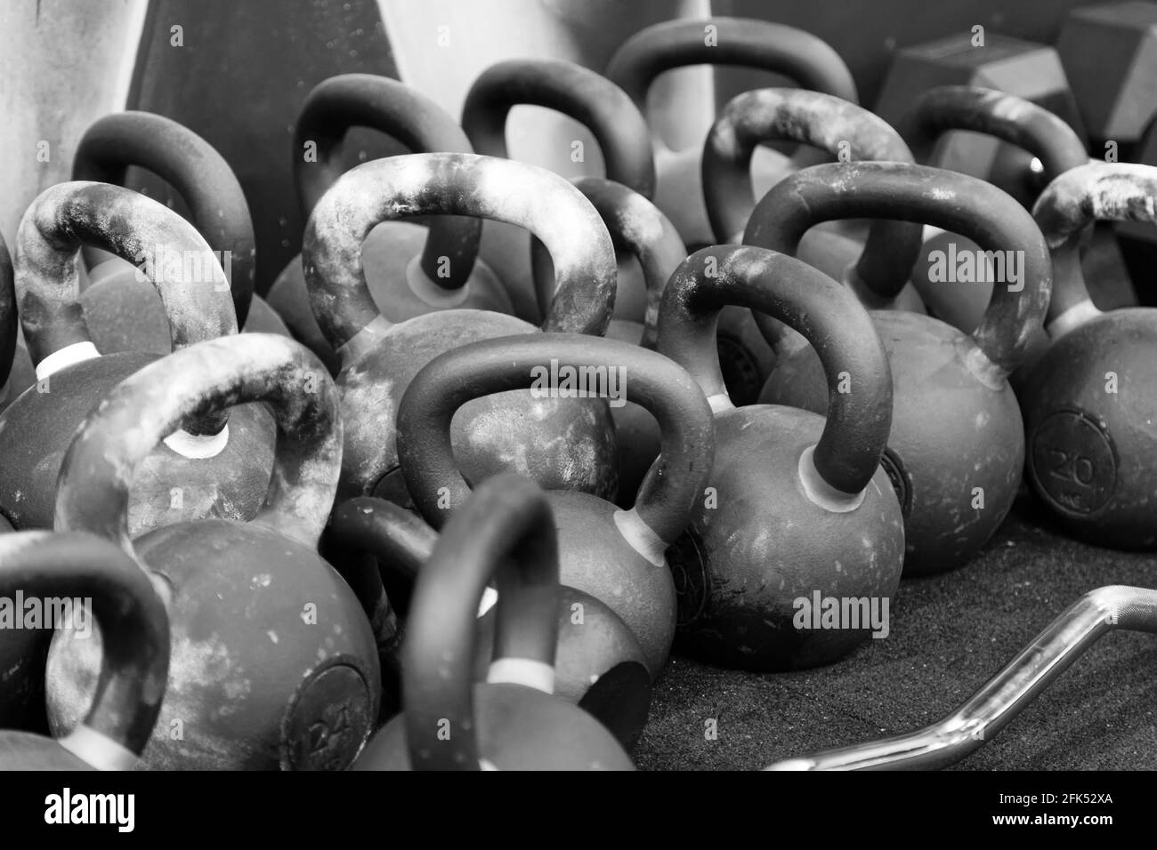 Nahaufnahme einer Reihe von Kurzhanteln auf dem Boden im Fitnessstudio. Schwarzweißbild mit flachem Fokus. Stockfoto