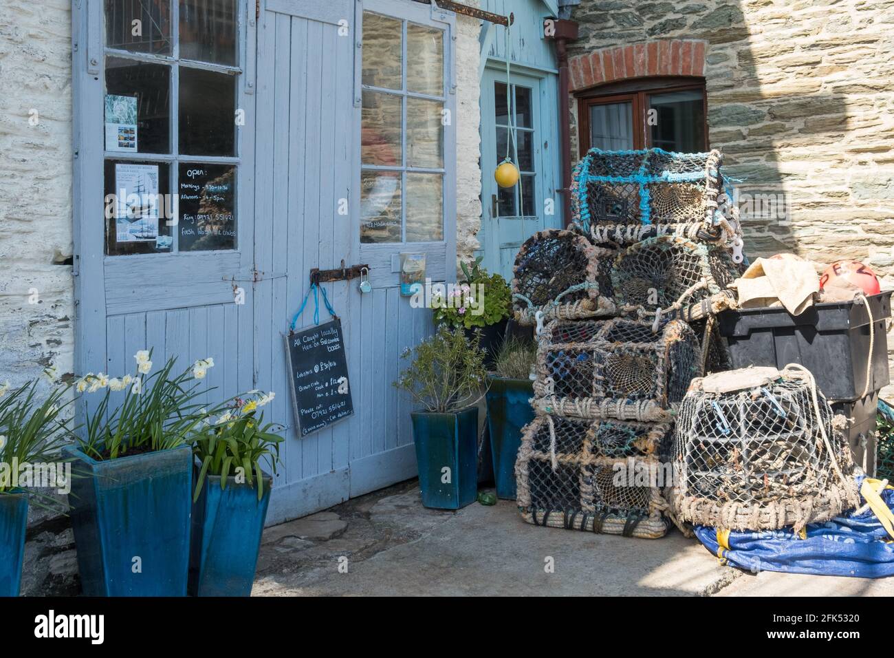 Krabben- und Hummertöpfe stapelten sich am Kai vor einem Geschäft, in dem frische Krabben und Hummer in Salcombe, South Hams, Devon verkauft werden Stockfoto