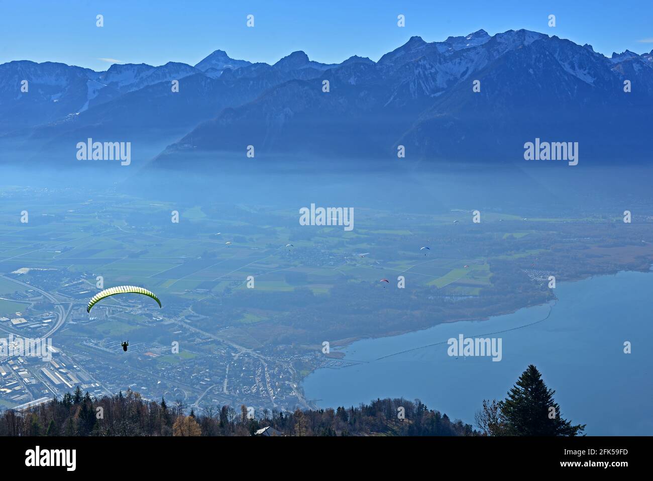 Gleitschirmflieger über dem Genfersee in der Schweiz mit schneebedeckten Bergen Im Hintergrund Stockfoto