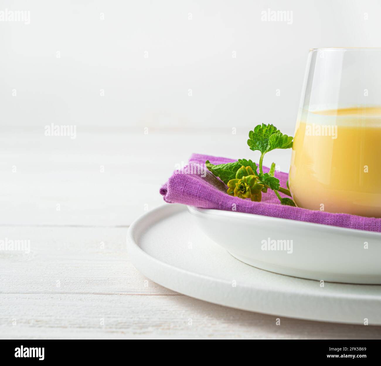 Hintergrund mit einem Teil eines Glases mit einem Milch-Mango-Getränk auf einem hellen Hintergrund. Stockfoto