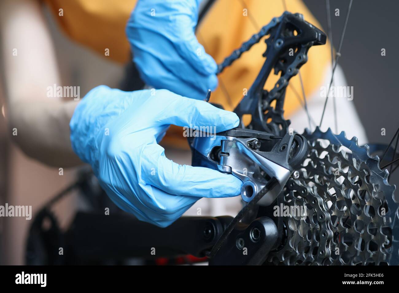 Handwerker in Gummihandschuhen Reparatur Fahrrad in der Werkstatt Nahaufnahme Stockfoto