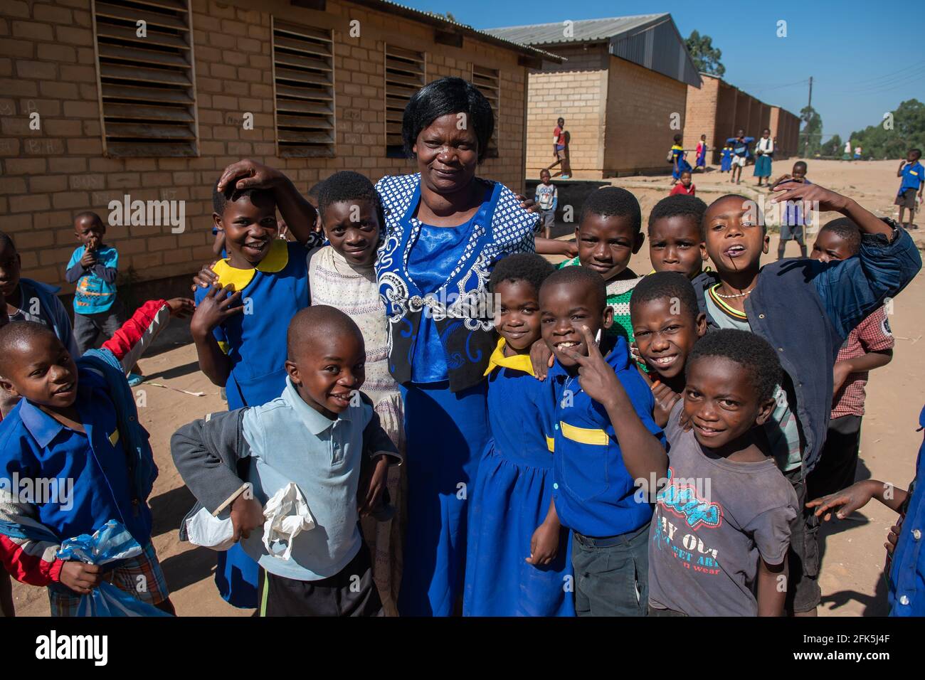 Mzuzu, Malawi. 30-05-2018. Ein afroabkömmlicher Lehrer mit Schülern lacht zusammen und schaut auf die Kamera auf dem Schulgelände in einer ländlichen Villa Stockfoto