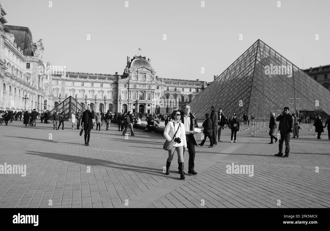 PARIS, FRANKREICH - 12. MÄRZ 2016: Touristen in der Nähe der Pyramide des Louvre bei Sonnenuntergang. Der Louvre ist das meistbesuchte Museum der Welt. Schwarzweißfoto Stockfoto