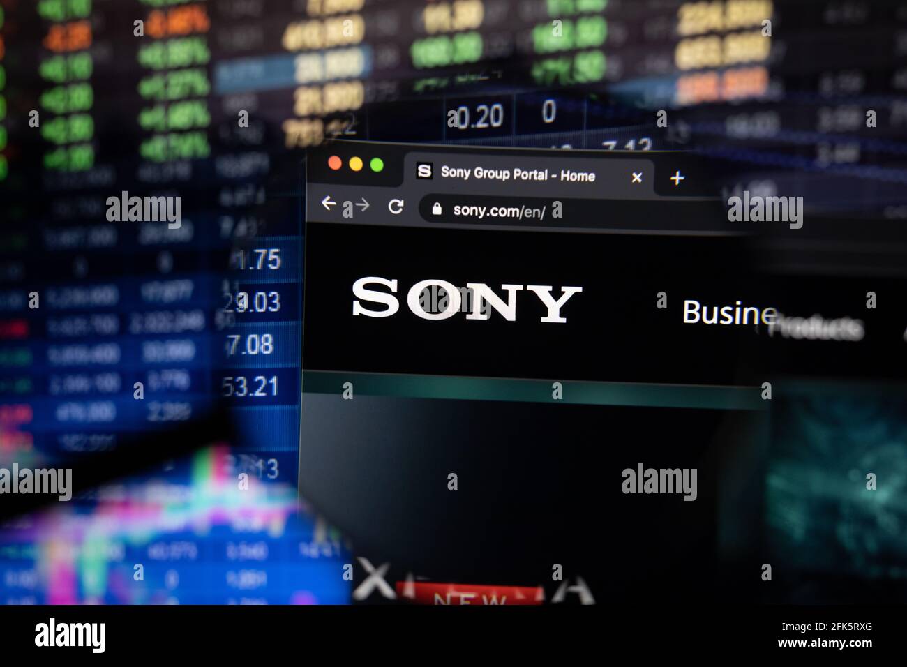 Sony Firmenlogo auf einer Website mit verschwommenen Entwicklungen an den Aktienmärkten im Hintergrund, die auf einem Computerbildschirm durch eine Lupe gesehen werden Stockfoto